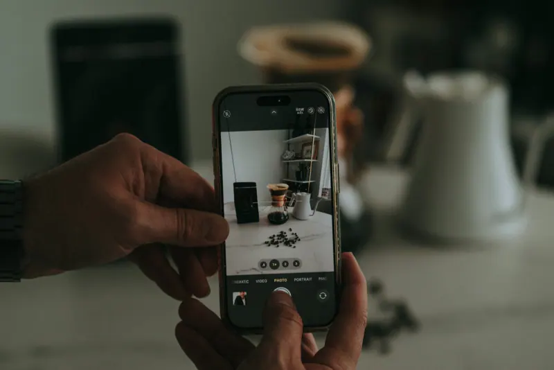 Manos tomando con el celular una foto de productos de café sobre una mesa