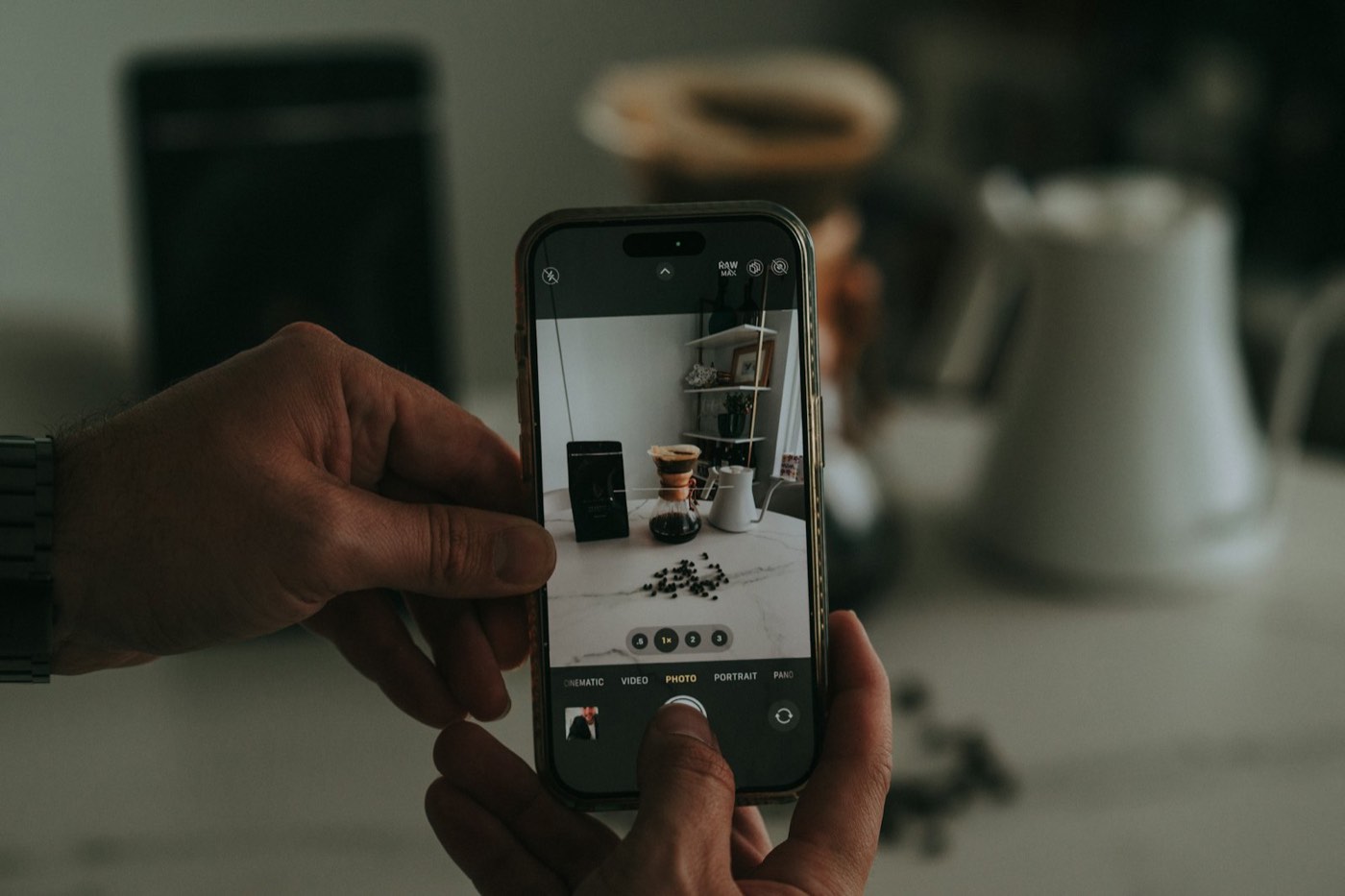 Manos tomando con el celular una foto de productos de café sobre una mesa