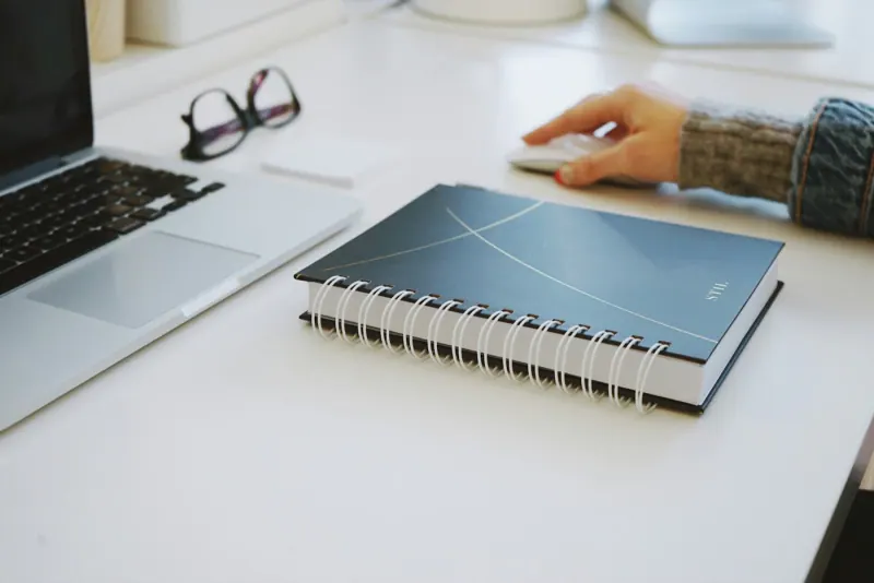 Desk with a laptop and notebook where someone organizes their customer follow-ups