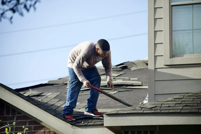 Contractor removing old shingles from a residential roof