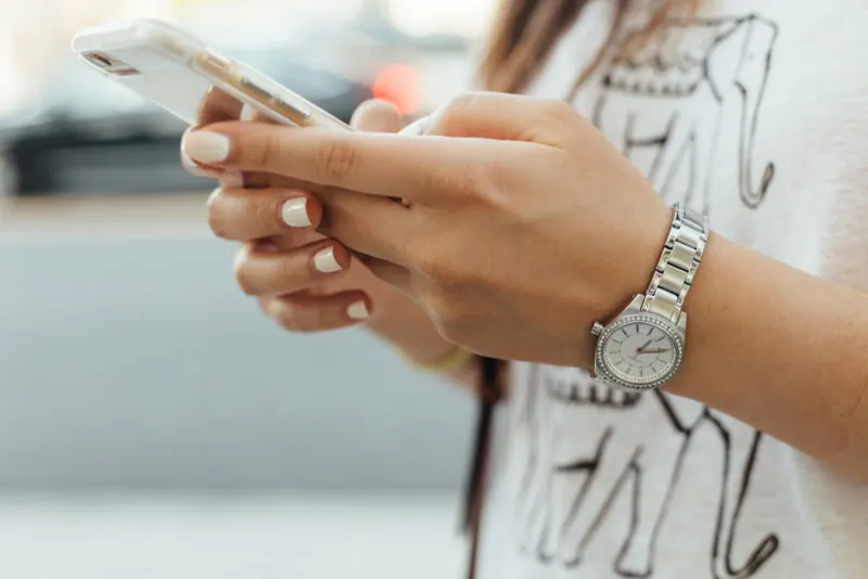 Close-up of hands typing a message on a smartphone