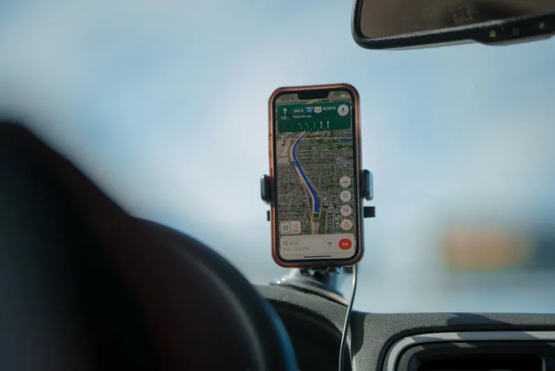 Celular montado en el tablero de un auto muestra una ruta de navegación en un mapa