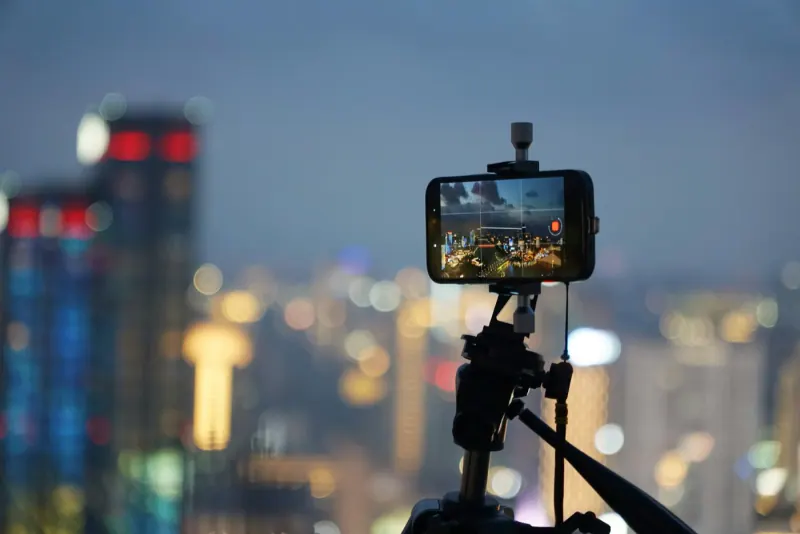 Celular en un tripié grabando video de la ciudad de noche