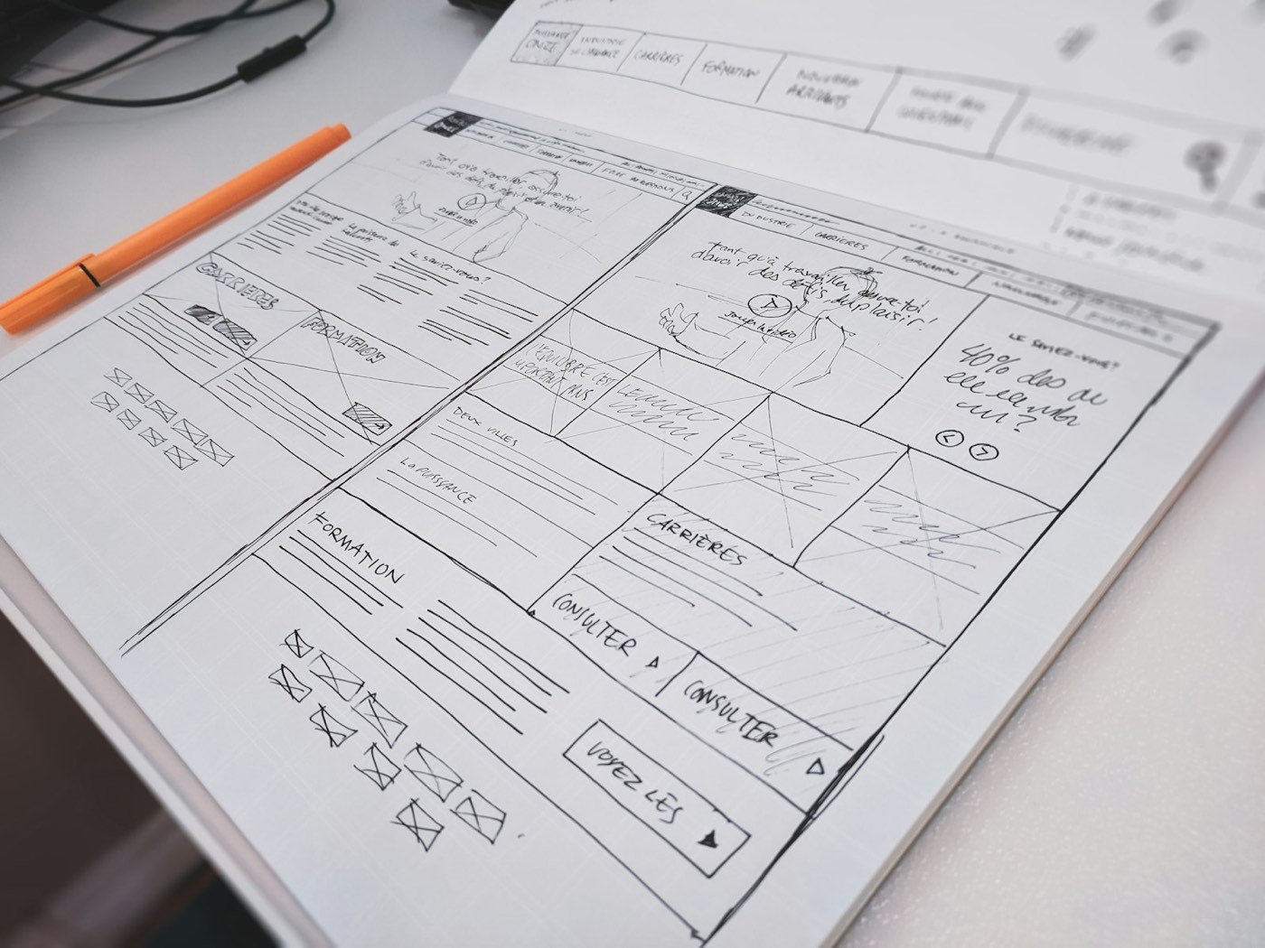 Boceto a mano del diseño de una página web sobre papel con una pluma naranja