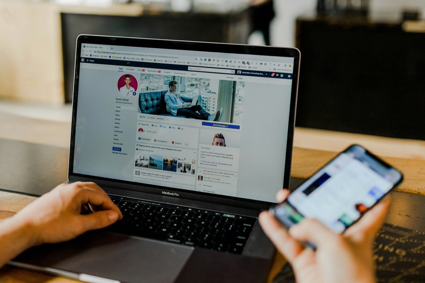 Person reviewing a social media page on a laptop while using their phone