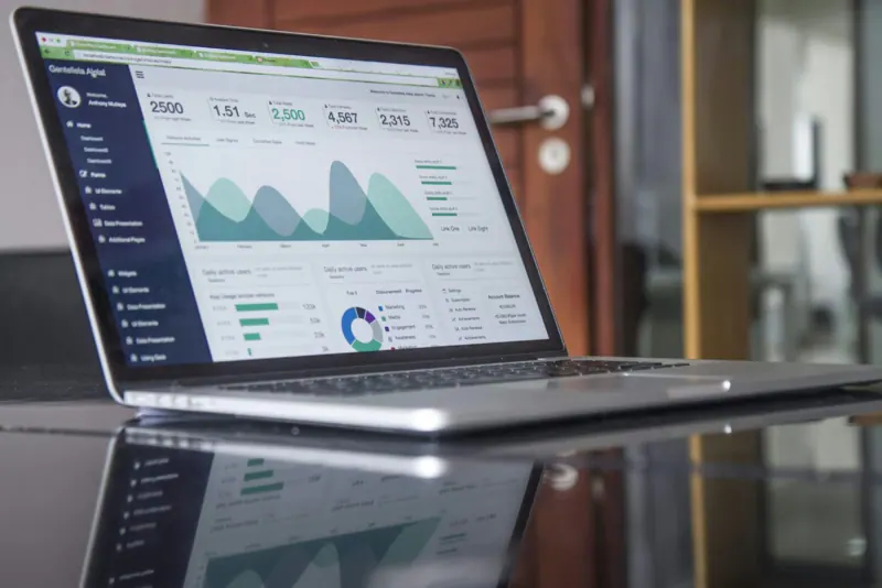 Laptop sobre una mesa de cristal mostrando un tablero con gráficas de resultados