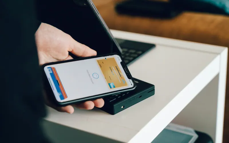 Person holding a phone up to a terminal to make a contactless payment