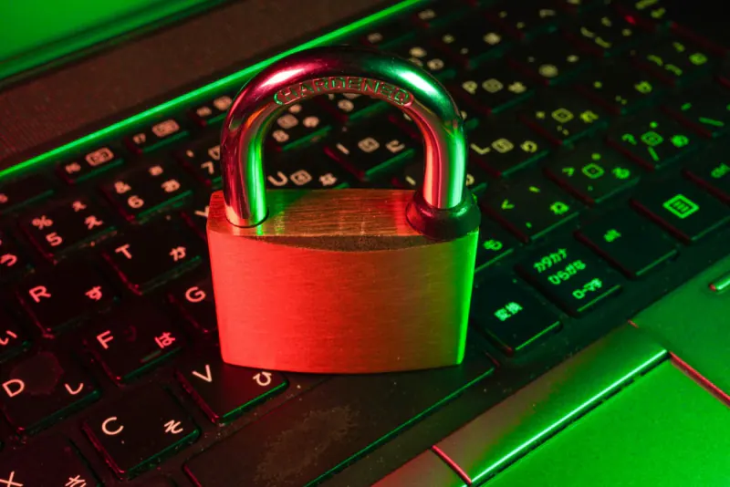 Candado metálico sobre el teclado de una computadora iluminado en rojo y verde