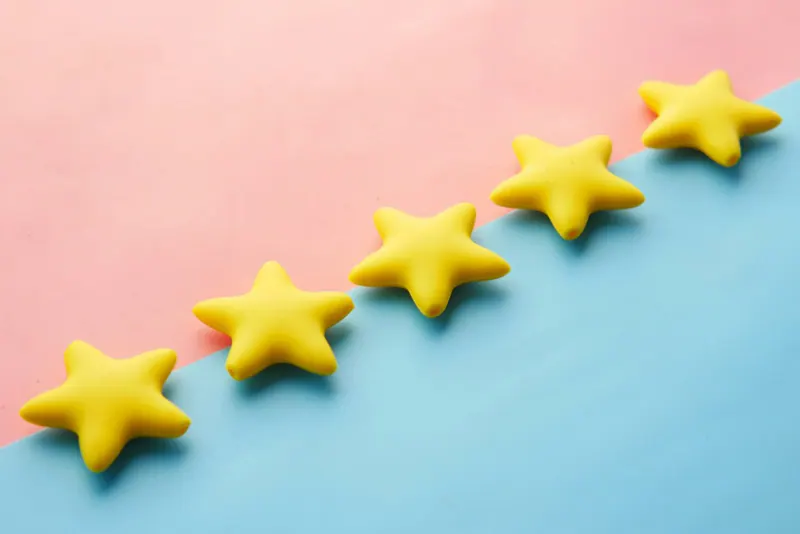 Cinco estrellas amarillas alineadas en diagonal sobre un fondo rosa y azul
