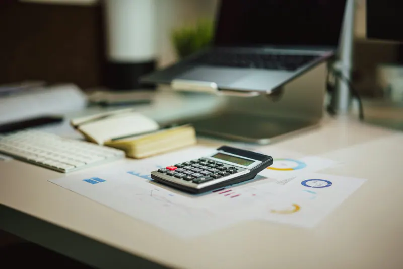 Calculadora sobre una mesa junto a una laptop