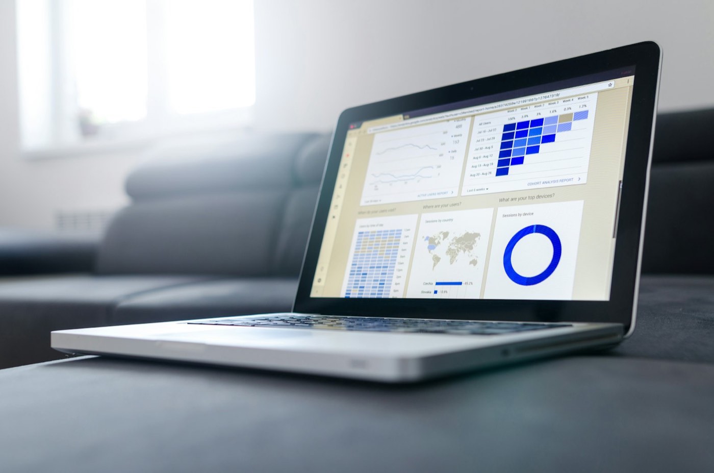 Laptop sobre un sillón mostrando un tablero de analítica con gráficas