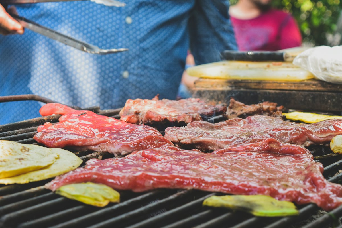 Taquero cortando carne asada recién salida de la parrilla