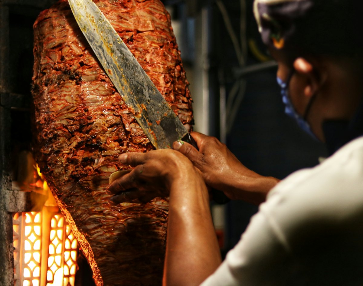Taquero rebanando carne al pastor del trompo