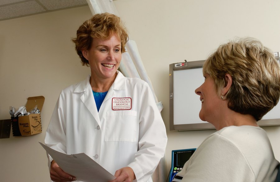 Doctora sonriendo mientras platica con una paciente en el consultorio