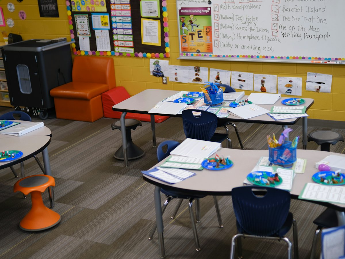 Salón de primaria con mesas de trabajo en equipo y materiales