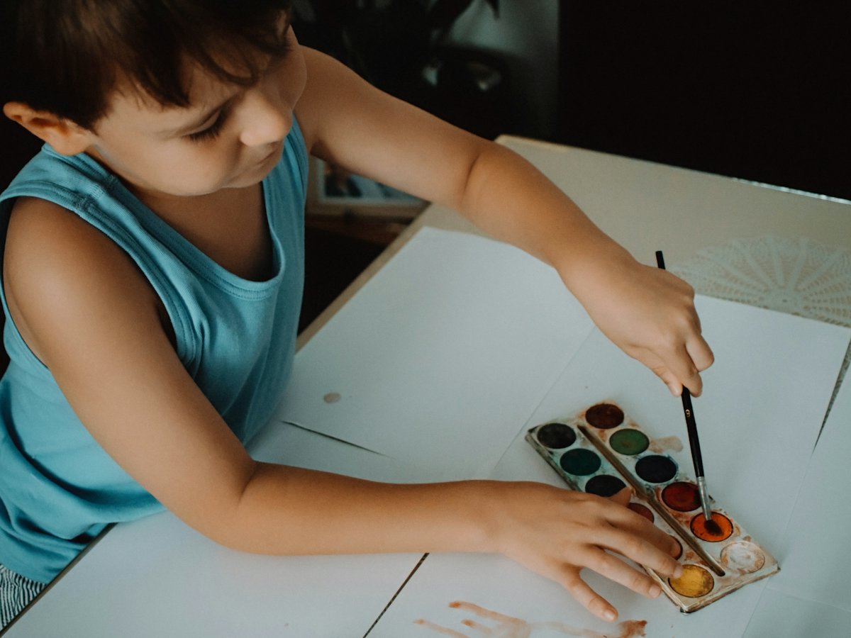 Niño pintando con acuarelas sobre una mesa