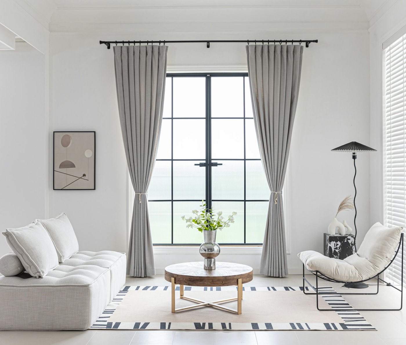 Sala luminosa con cortinas de lino gris a todo lo alto del ventanal