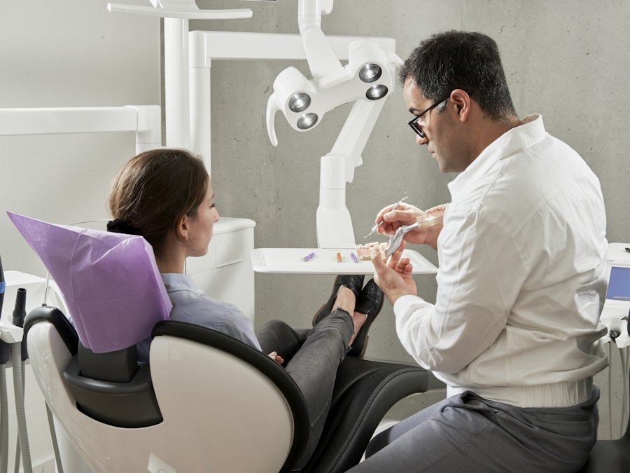 Dentista explicando un modelo dental a una paciente sentada en el sillón