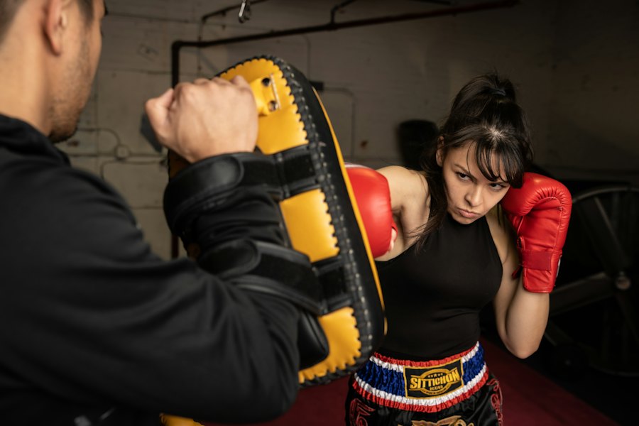 Mujer con guantes rojos golpeando manoplas con su coach