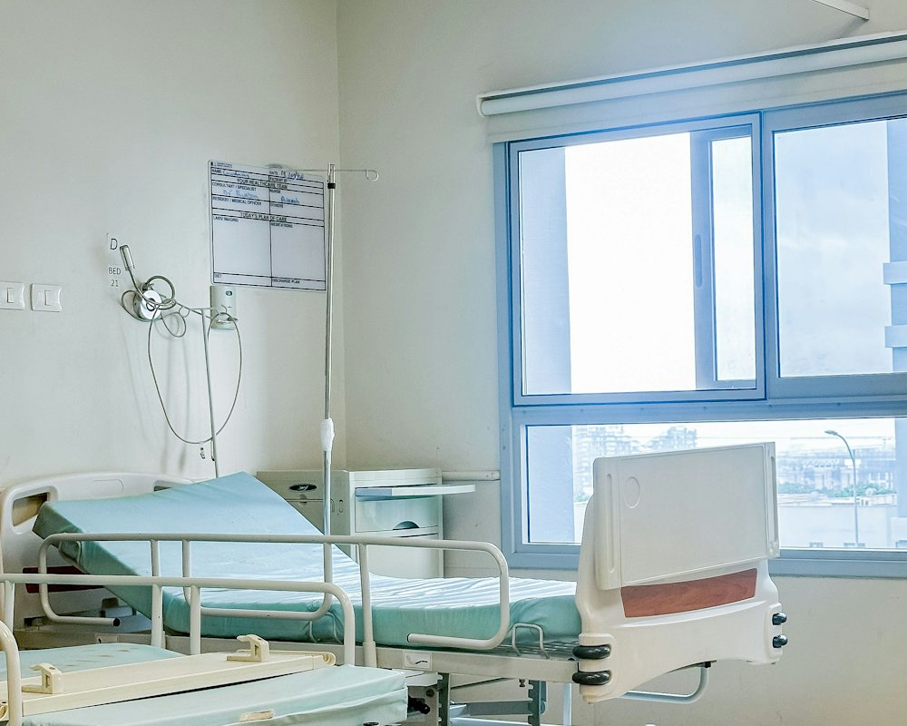 Habitación privada de hospital con cama, sillón y ventanal luminoso