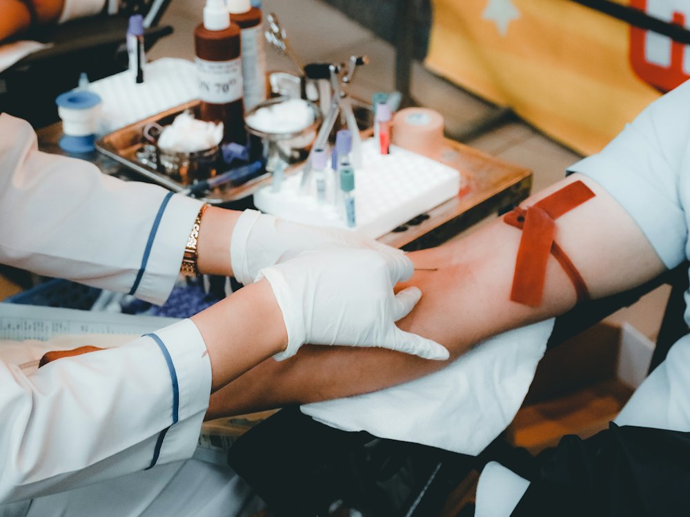 Enfermera con guantes tomando una muestra de sangre del brazo de un paciente