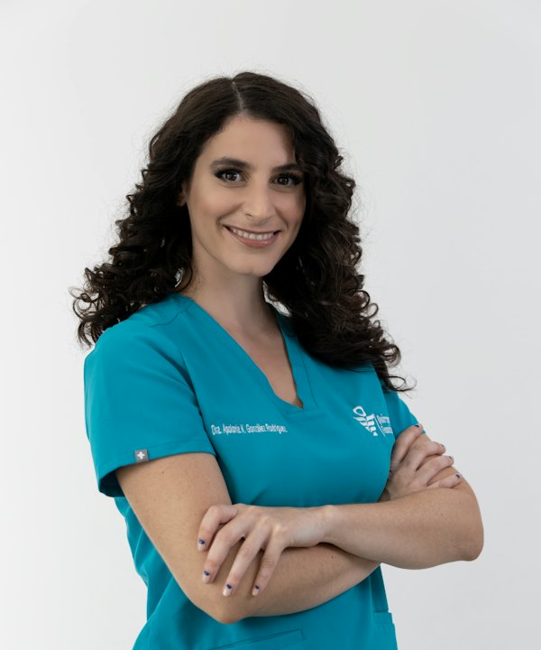 Doctora con uniforme quirúrgico turquesa, de brazos cruzados y sonriendo