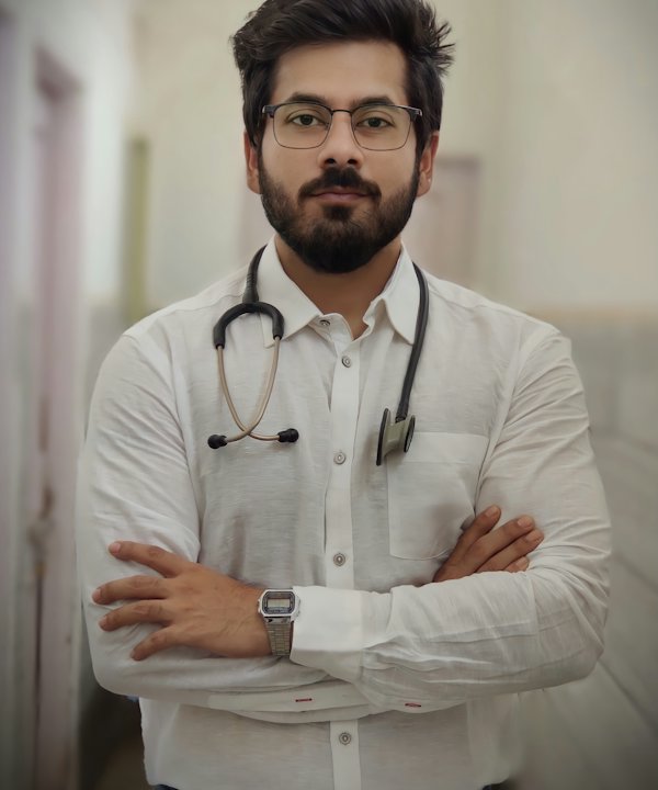 Médico de barba con camisa blanca y estetoscopio, de brazos cruzados