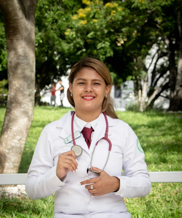 Doctora sonriente con bata blanca y estetoscopio al aire libre