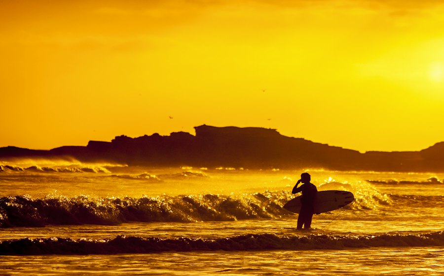 Atardecer en la playa con un surfista