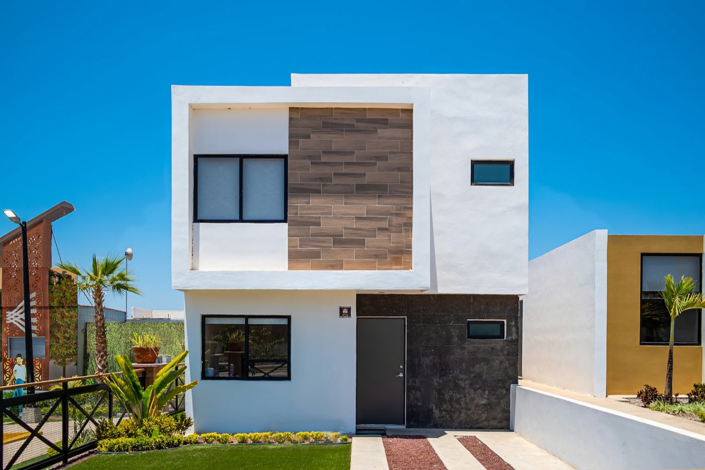 Fachada de casa contemporánea blanca con celosía de madera y cielo azul