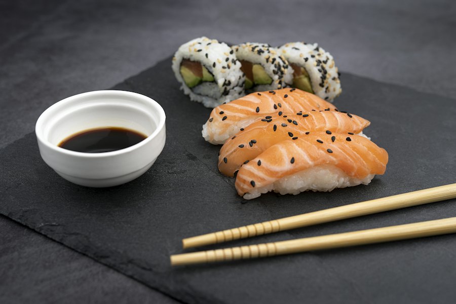 Nigiris de salmón y rollos sobre pizarra con salsa de soya