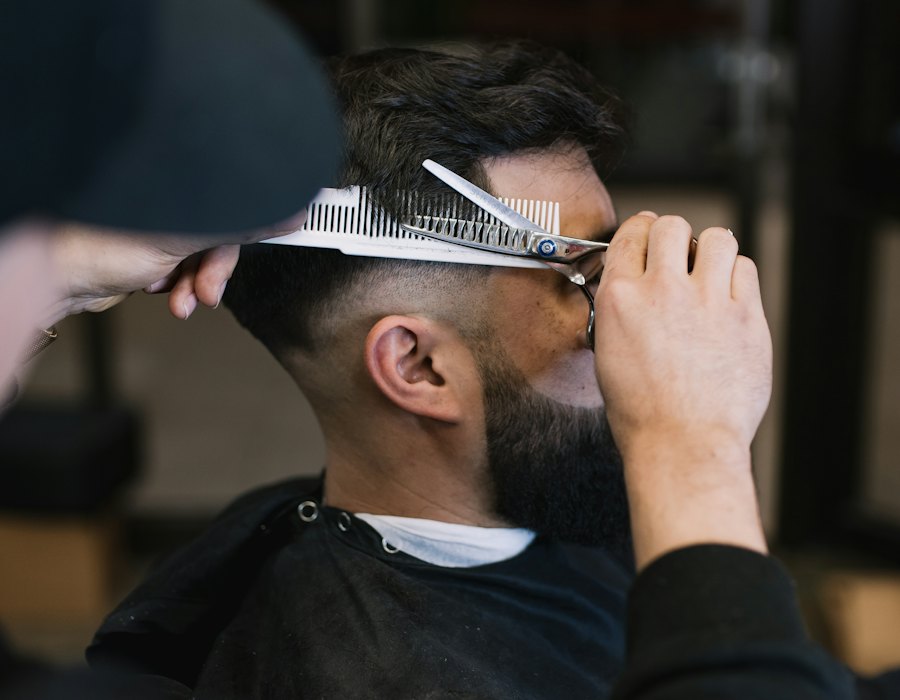 Barbero marcando un fade con tijera y peine a un cliente con barba