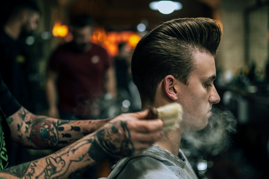 Barbero peinando un pompadour con brocha en la barbería