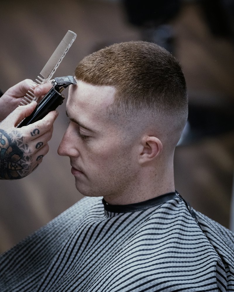 Barbero marcando un fade alto con máquina y peine