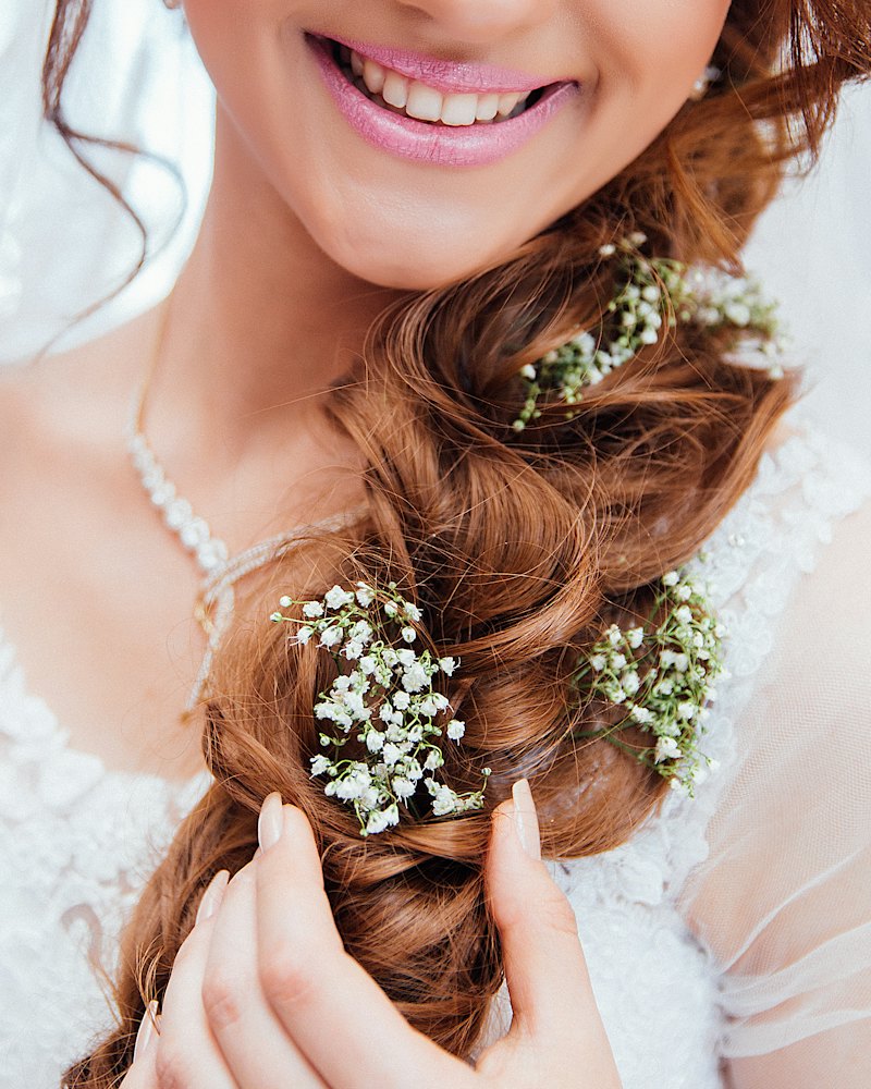 Novia sonriendo con trenza lateral adornada con flores blancas
