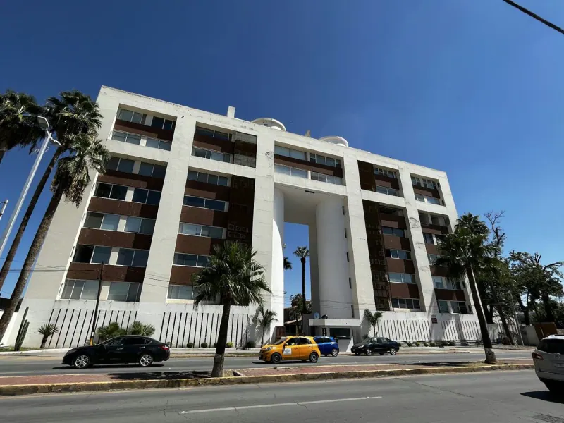 Edificio de departamentos con palmeras sobre un bulevar de Torreón, Coahuila, bajo cielo despejado