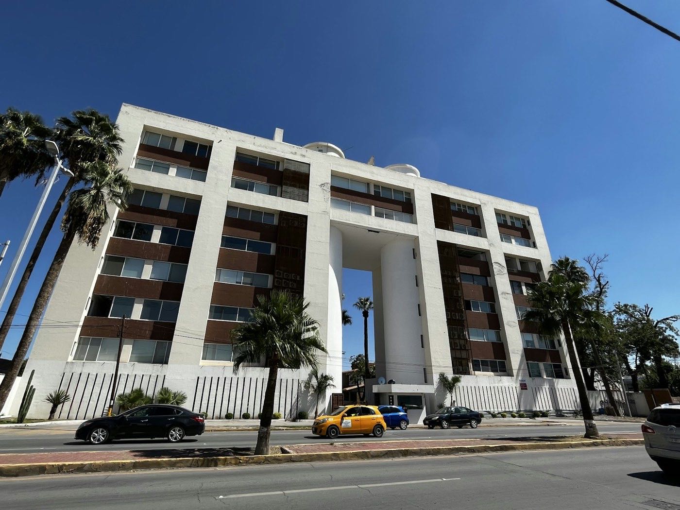 Edificio de departamentos con palmeras sobre un bulevar de Torreón, Coahuila, bajo cielo despejado